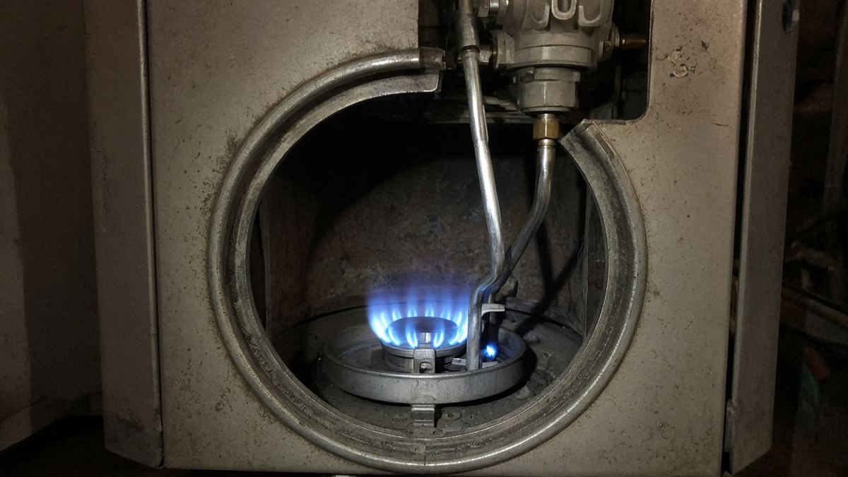 Blue burner flame and pilot inside the combustion chamber of a gas water heater